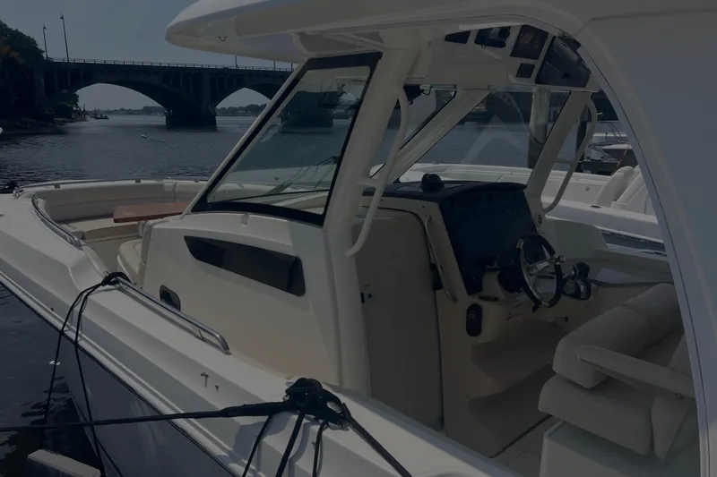 Slide: The Image of 2020 Boston Whaler 350 Realm boat interior with steering wheel, docked near a bridge. - 10