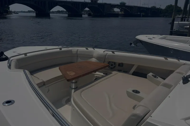 Slide: The Image of 2020 Boston Whaler 350 Realm boat interior with seating and table, near a bridge. - 13