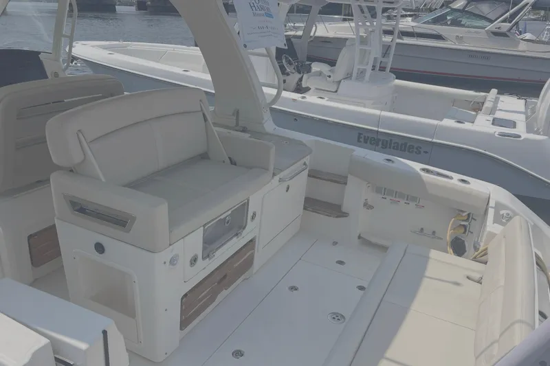 Slide: The Image of 2020 Boston Whaler 350 Realm boat interior with seating and storage, docked near other boats. - 8