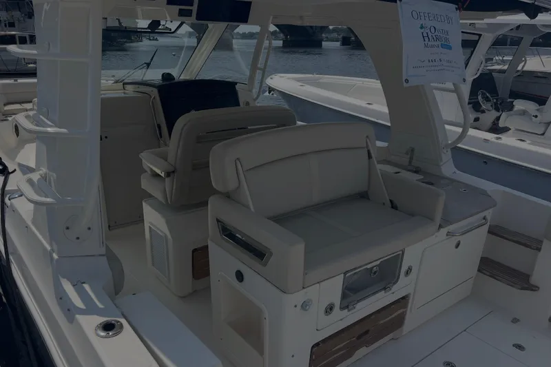 Slide: The Image of 2020 Boston Whaler 350 Realm interior with seating and helm, docked by the water. - 9