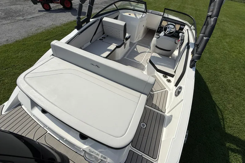 Slide: The Image of 2025 Sea Ray SPX 210 Outboard boat interior with seating and steering wheel on grass. - 3