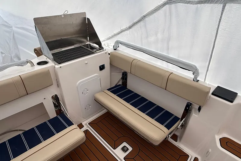 Slide: The Image of 2025 Ranger Tugs R-25 boat interior with seating and grill, featuring teak flooring. - 10