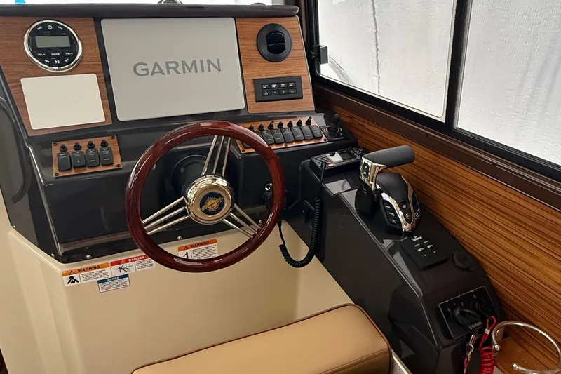 Slide: The Image of 2025 Ranger Tugs R-25 helm with Garmin navigation, wood accents, and modern controls. - 19
