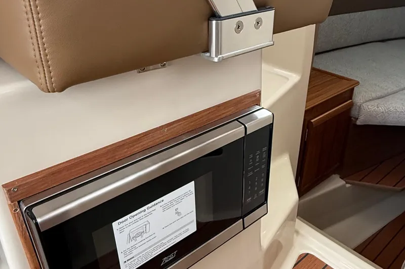 Slide: The Image of 2025 Ranger Tugs R-25 interior with microwave and wooden cabinetry. - 38