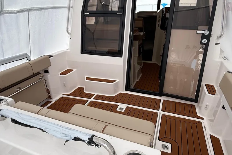 Slide: The Image of 2025 Ranger Tugs R-25 boat interior with teak flooring and beige seating. - 5