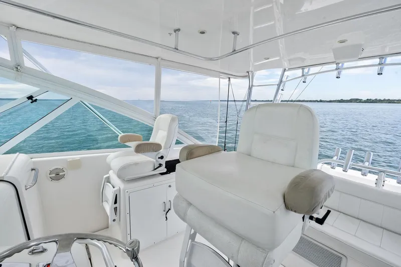 Slide: The Image of 2004 Cabo 40 Hardtop Express yacht interior with ocean view, featuring white seating and helm. - 12
