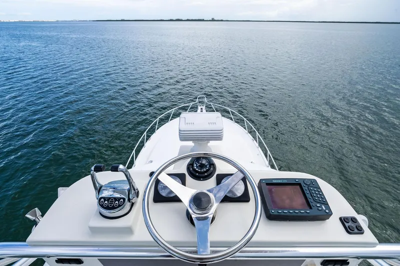 Slide: The Image of Helm view of 2004 Cabo 40 Hardtop Express yacht on open water. - 18