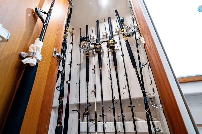 Slide: The Image of Fishing rods stored vertically in a wooden cabinet on a 2004 Cabo 40 Hardtop Express boat. - 25