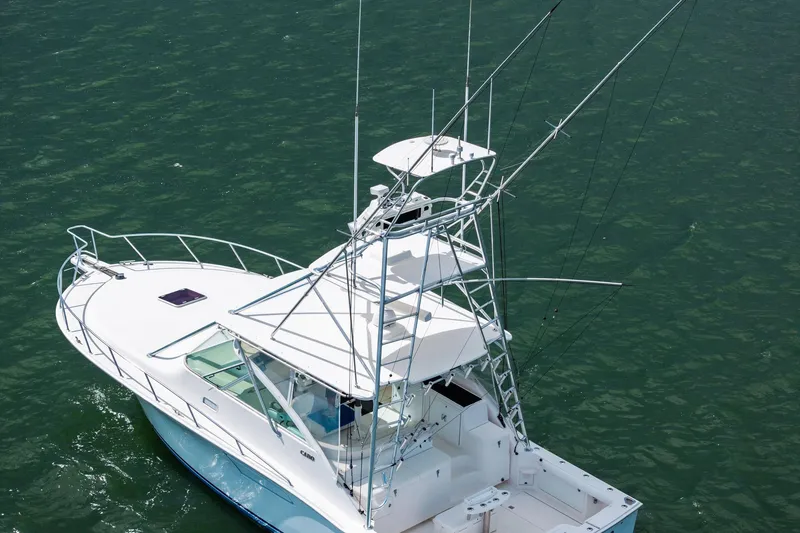 Slide: The Image of 2004 Cabo 40 Hardtop Express boat on water, featuring a sleek design and fishing tower. - 5