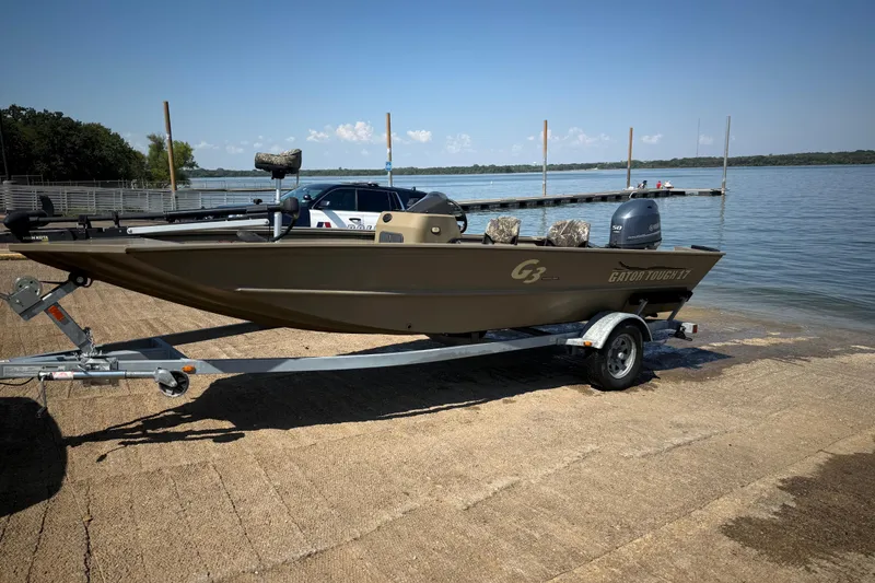 Slide: The Image of 2020 G3 Gator Tough 17 SC boat on trailer by a lake dock. - 17