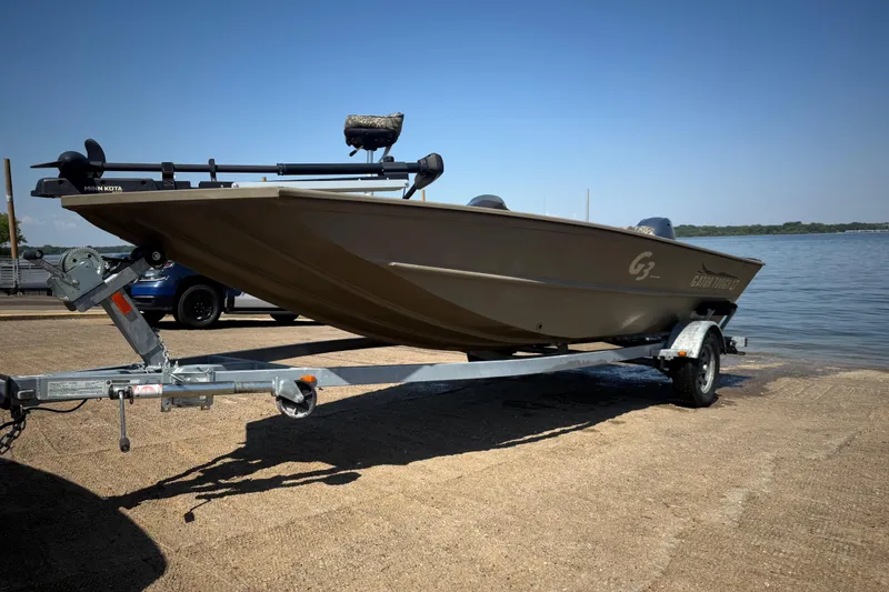 Slide: The Image of 2020 G3 Gator Tough 17 SC boat with Minn Kota trolling motor, parked near water. - 19