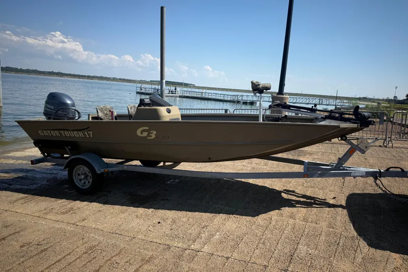 Slide: The Image of 2020 G3 Gator Tough 17 SC boat on trailer by a lake. - 2