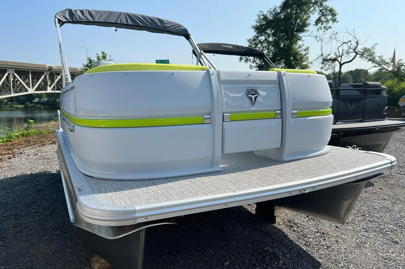 Slide: The Image of 2026 Tahoe Pontoon AURA 1985, white with green accents, docked near a bridge. - 3