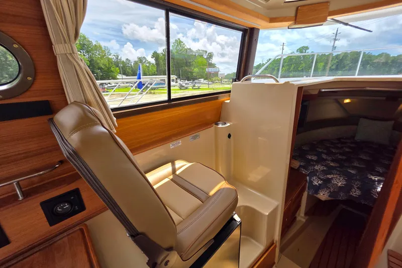 Slide: The Image of 2020 Ranger Tugs R27LE interior kitchen with stove, sink, and wooden cabinetry. - 16