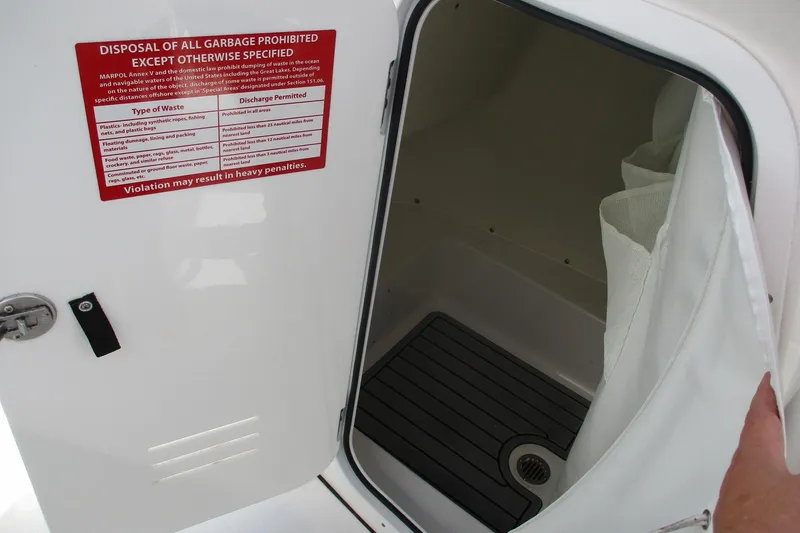 Slide: The Image of 2023 Tidewater 210 LXF boat storage compartment with waste disposal warning sign. - 11