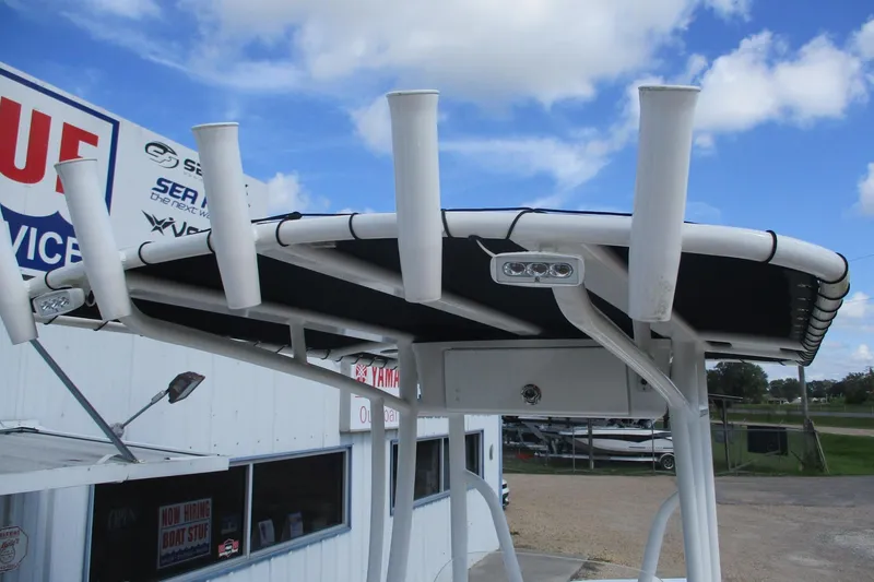 Slide: The Image of 2023 Tidewater 210 LXF boat with rod holders and canopy, displayed outdoors. - 23