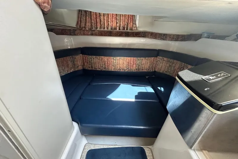 Slide: The Image of 1998 Chris-Craft 320 Express Cruiser interior with blue seating and patterned curtains. - 11