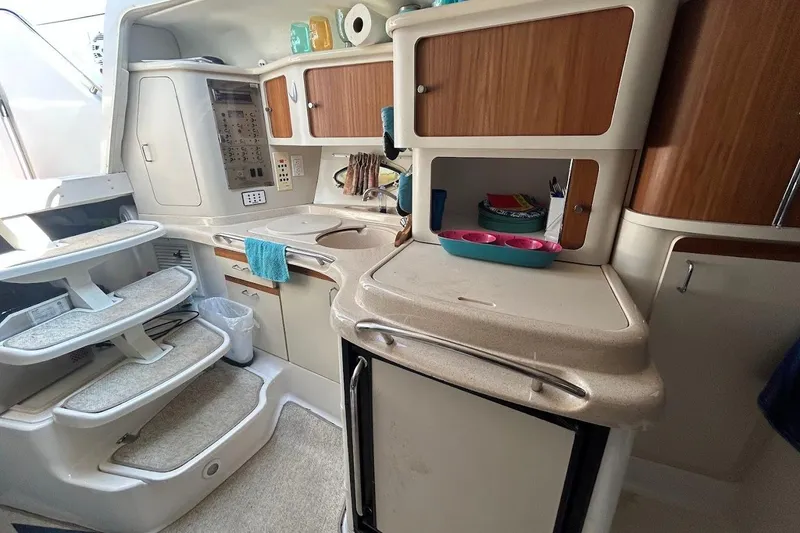 Slide: The Image of 1998 Chris-Craft 320 Express Cruiser interior with kitchenette, wooden cabinets, and stairs. - 13