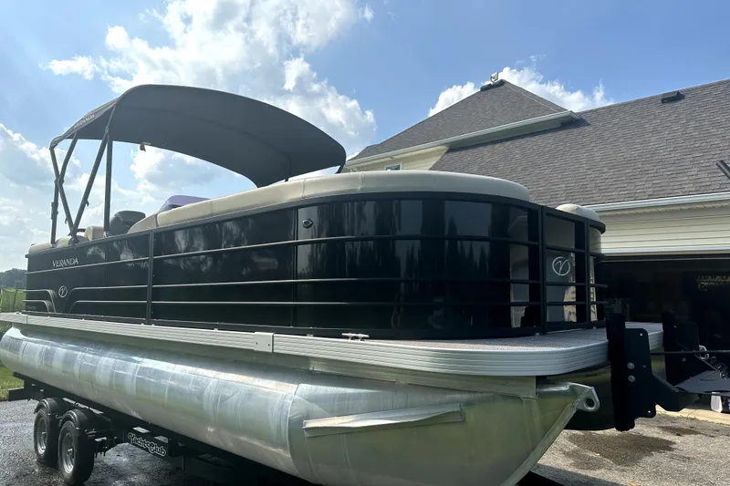Slide: The Image of 2021 Veranda Vista 22RC pontoon boat parked near a house under a clear sky. - 7