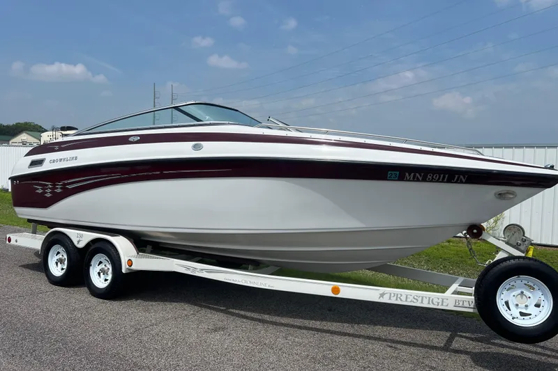 The Image of 2003 Crownline 230 BR boat on trailer, parked outdoors under a clear sky. - 0