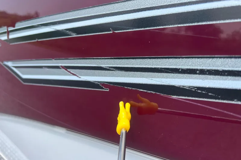 Slide: The Image of Close-up of 2003 Crownline 230 BR boat with peeling decal and yellow tool. - 13