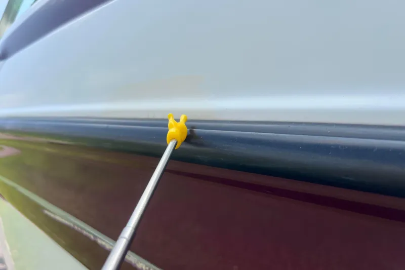 Slide: The Image of Close-up of a 2003 Crownline 230 BR boat with a yellow tool on the hull. - 23