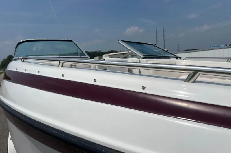 Slide: The Image of 2003 Crownline 230 BR boat with maroon stripe, sleek design, and open cockpit. - 29
