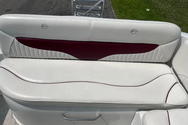 Slide: The Image of 2003 Crownline 230 BR boat seat with white and maroon upholstery, outdoor setting. - 32