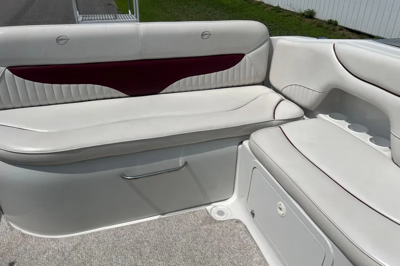 Slide: The Image of 2003 Crownline 230 BR boat interior with white and maroon seating, cup holders, and storage. - 34