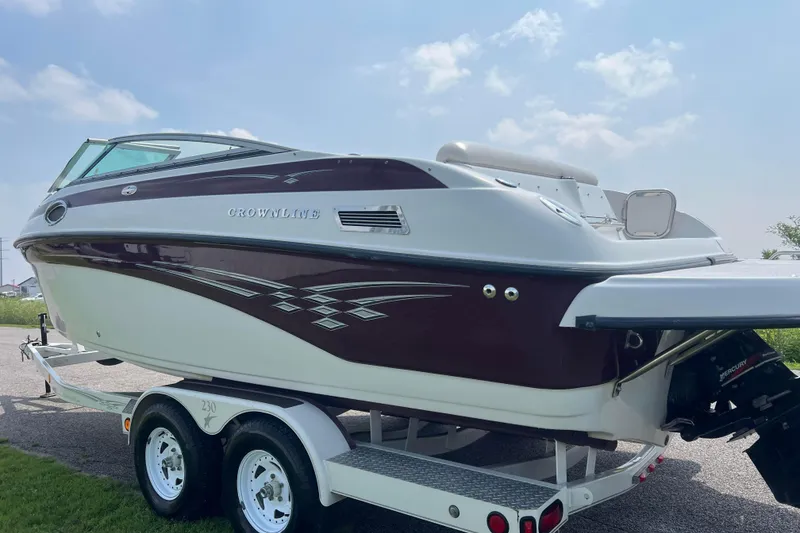 Slide: The Image of 2003 Crownline 230 BR boat on trailer, maroon and white design, sunny day. - 7