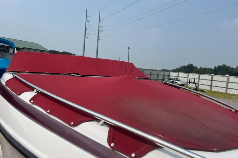 Slide: The Image of 2003 Crownline 230 BR boat with red cover, parked outdoors. - 70
