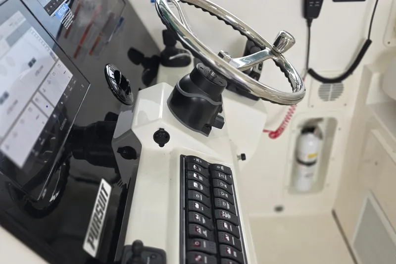 Slide: The Image of 2024 Pursuit DC 326 Dual Console helm with steering wheel and control panel. - 12