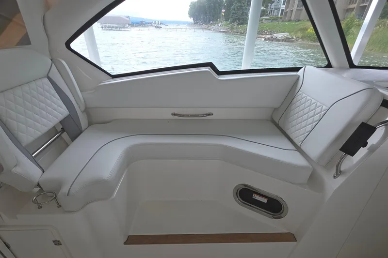 Slide: The Image of 2024 Pursuit DC 326 Dual Console interior with white seating and waterfront view. - 15