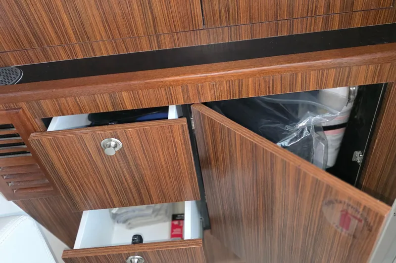 Slide: The Image of 2024 Pursuit DC 326 Dual Console interior with open wooden cabinets and drawers. - 27