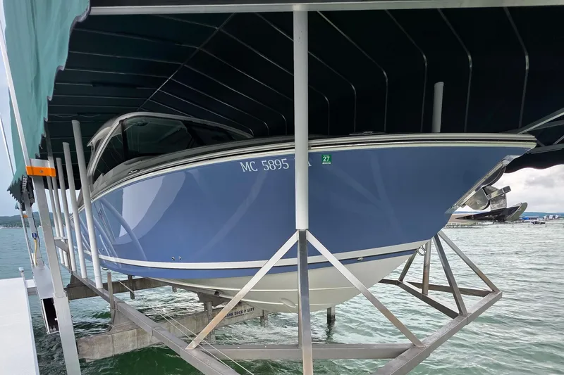 Slide: The Image of 2024 Pursuit DC 326 Dual Console boat on lift, blue hull, docked at marina. - 3