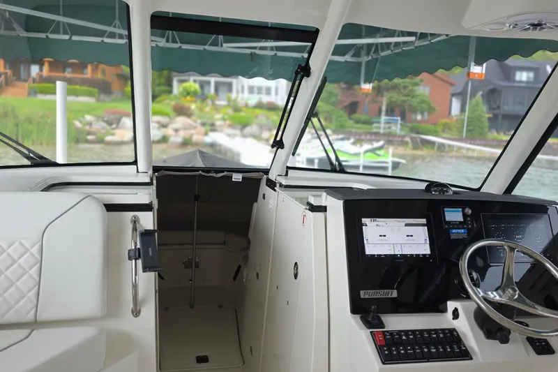 Slide: The Image of 2024 Pursuit DC 326 Dual Console interior with steering wheel and dashboard, dockside view. - 8