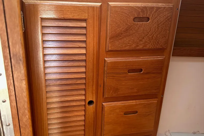 Slide: The Image of Wooden cabinetry inside a 1998 Catalina 36 MkII sailboat, featuring louvered door and drawers. - 20