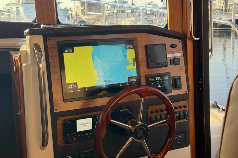 Slide: The Image of 2024 Ranger Tugs R31CB helm with navigation display and wooden steering wheel. - 18