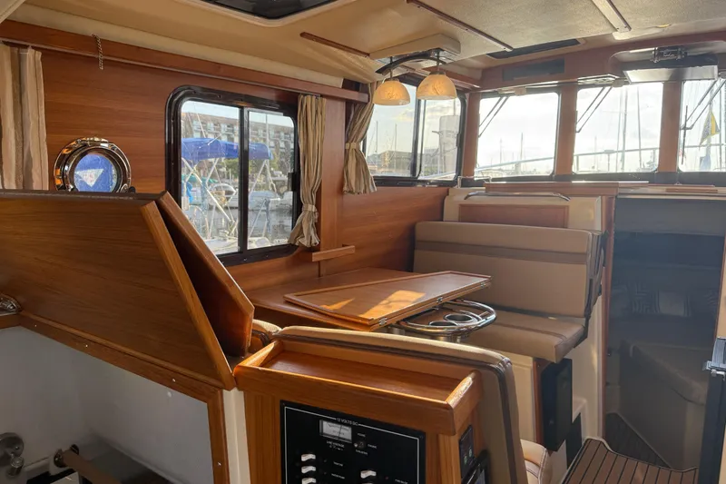 Slide: The Image of 2024 Ranger Tugs R31CB interior with wood finish, seating, and windows. - 19