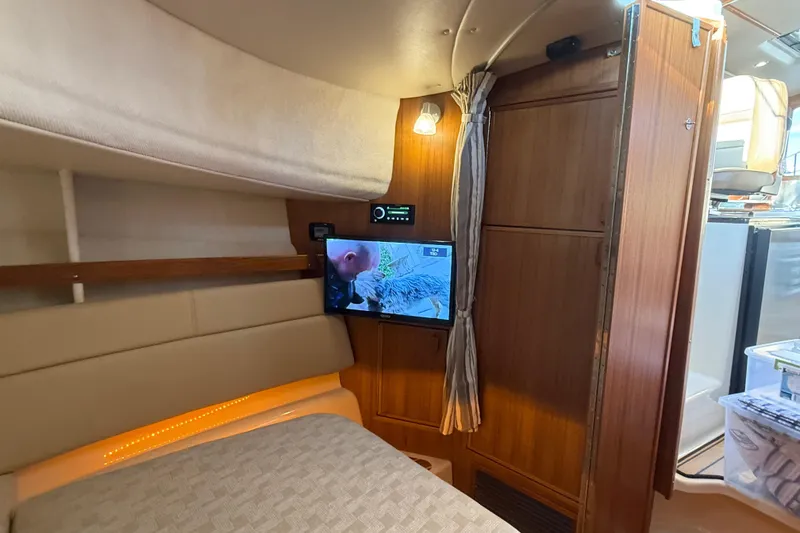 Slide: The Image of 2024 Ranger Tugs R31CB cabin interior with TV, wood paneling, and cozy lighting. - 24