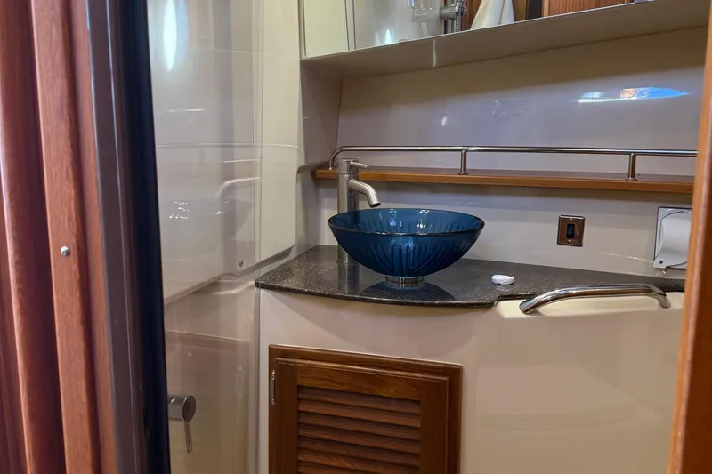 Slide: The Image of 2024 Ranger Tugs R31CB bathroom with elegant blue glass sink and modern fixtures. - 26