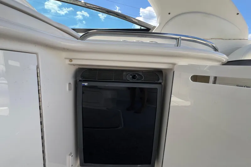 Slide: The Image of 2005 Sea Ray 290 SLX boat interior with built-in mini fridge under blue sky. - 17