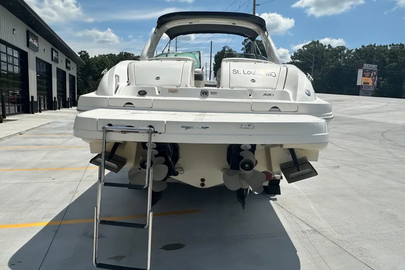 Slide: The Image of 2005 Sea Ray 290 SLX boat with ladder, parked outdoors on a sunny day. - 2