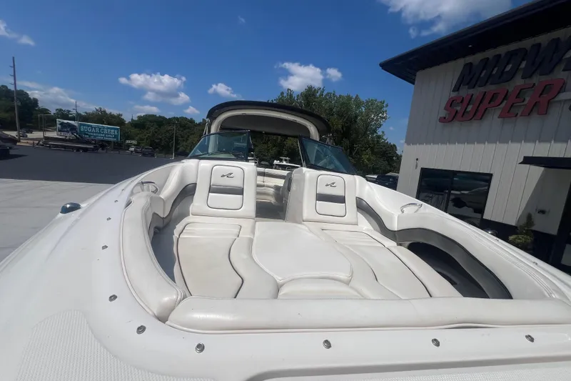 Slide: The Image of 2005 Sea Ray 290 SLX boat with white seating, parked outdoors under a blue sky. - 6