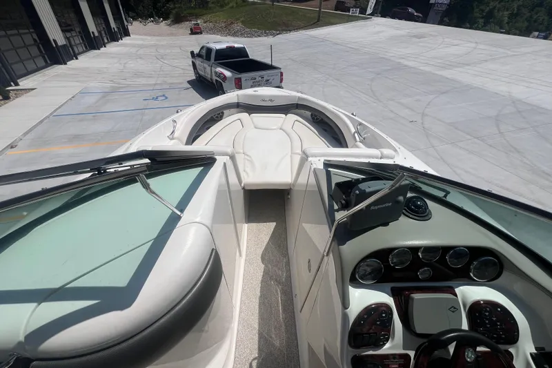 Slide: The Image of 2005 Sea Ray 290 SLX boat interior with dashboard and seating, parked near a truck. - 9