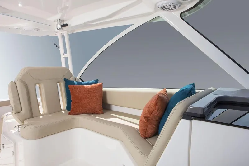 Slide: The Image of 2019 Pursuit DC 325 Dual Console boat interior with cushioned seating and colorful pillows. - 99