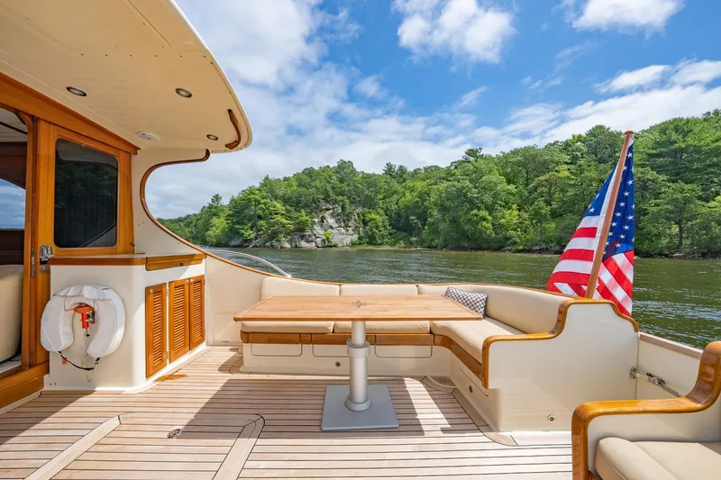 Slide: The Image of Luxurious 2007 Vicem 65 yacht deck with seating, table, and American flag, surrounded by scenic water and trees. - 10