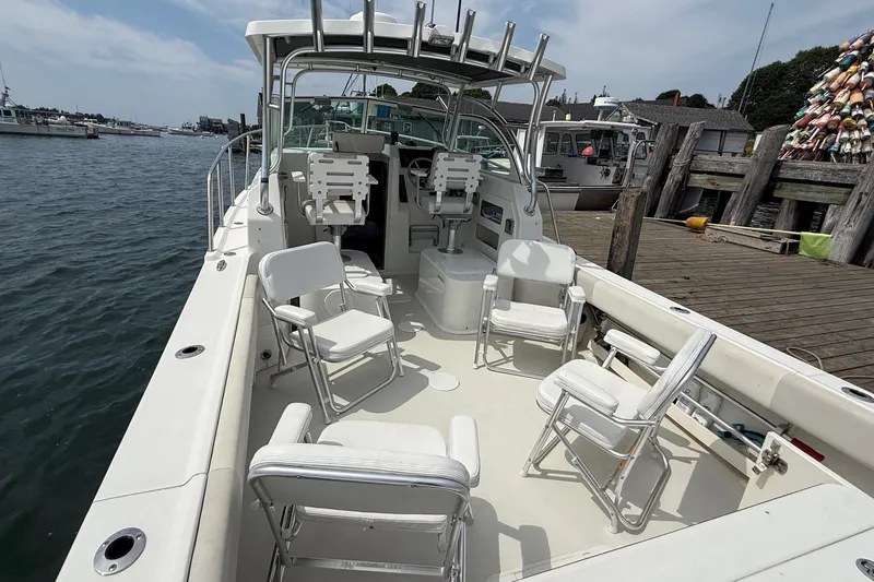 Slide: The Image of 2015 Parker 2510 XLD Walkaround boat docked, featuring spacious seating and fishing rod holders. - 12