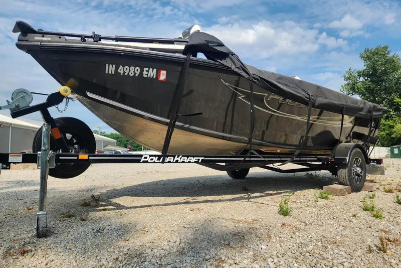 Slide: The Image of 2024 Polar Kraft Frontier 165 SCJ boat on trailer, covered, parked on gravel. - 2