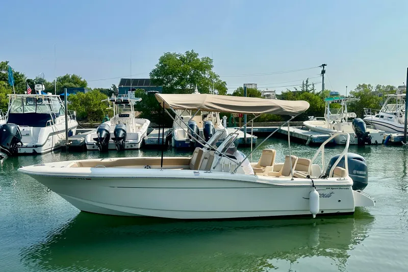 Slide: The Image of 2023 Scout 195 Sport Dorado boat docked in a marina with canopy and Yamaha engine. - 0